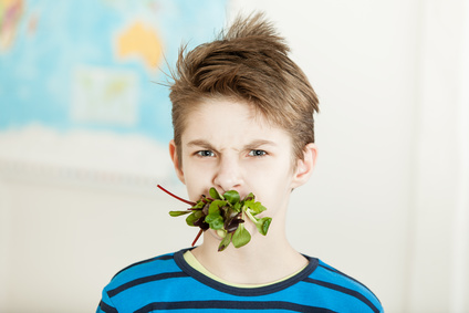 Ein Junge hat Salat im Mund