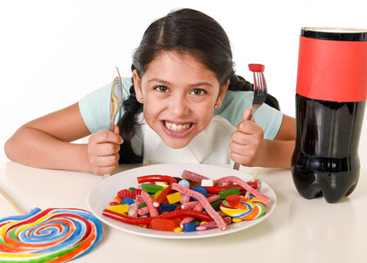 Kleines Mädchen mit Süßigkeiten auf dem Tisch